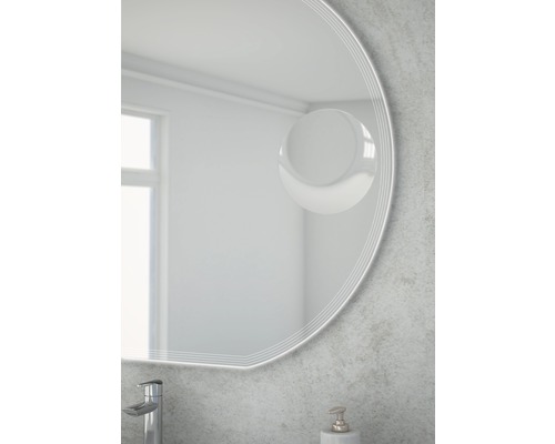 Detail kulatého zrcadla v koupelně s vodovodní baterií a dávkovačem mýdla