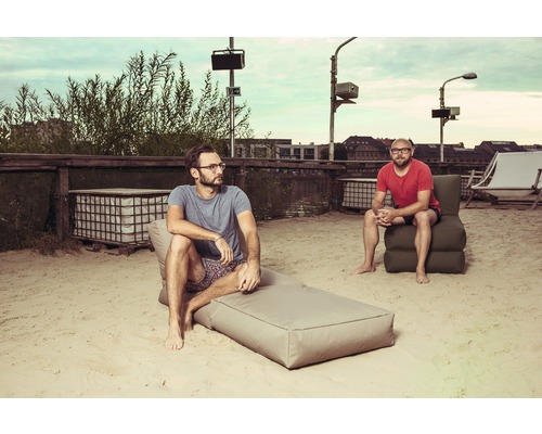 Dva muži relaxují na písečné ploše s venkovním nábytkem.