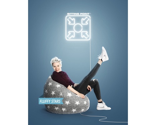 Žena sedí v šedém sedacím vaku se vzorem hvězdy pod logem ''Sitting Point''