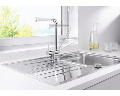 Nerezová dřezová baterie s otočným výtokem ve světlé kuchyni.