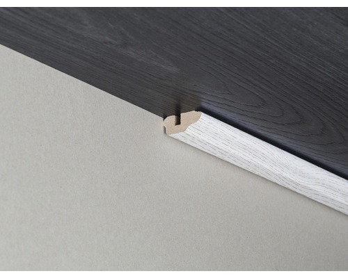 Podlahová lišta mezi stěnou a tmavou laminátovou podlahou