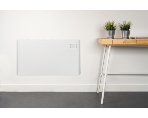 Bílý radiátor na zdi vedle psacího stolu s rostlinami