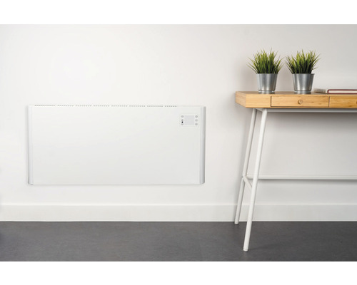 Nástěnný konvektorový ohřívač v místnosti se stolem a dekorací