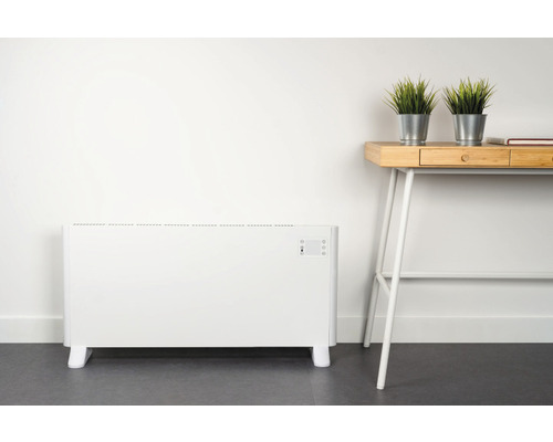 Elektrický radiátor vedle psacího stolu s dekorací