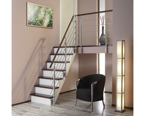 Interiér se schodištěm, křeslem a stojací lampou.