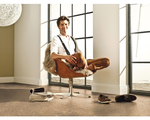 Světlá místnost s korkovou podlahou a muž v hnědém křesle