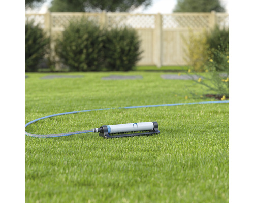 Zahradní zavlažovač s hadicí na trávníku