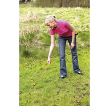 Žena používá odpalovač míčků na trávníku k odpalování míče