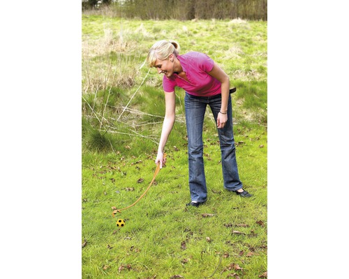 Žena používá odpalovač míčků na trávníku k odpalování míče