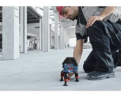 Stavební dělník s čárovým laserem Bosch Professional pro vyrovnání na staveništi