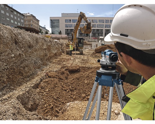 Stavební dělník pracující s nivelačním přístrojem na staveništi
