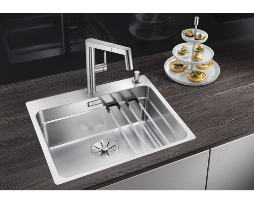 Nerezový dřez s odkapávačem a baterií na kuchyňské lince.