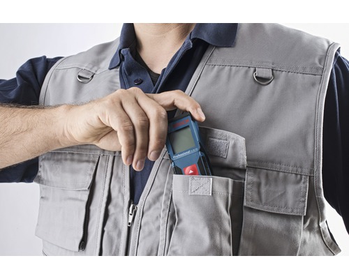 Ruka vkládá laserový dálkoměr do kapsy pracovní vesty