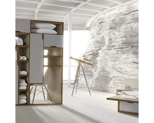 Světlá ložnice s šatní skříní, křeslem, teleskopem a dekorací kamenné stěny