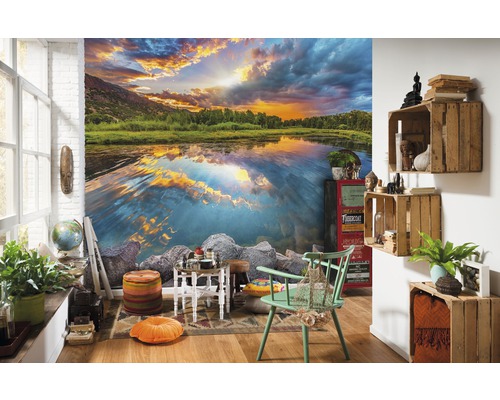 Obývací pokoj s fototapetou jezera při západu slunce, zdobený různým nábytkem a doplňky.