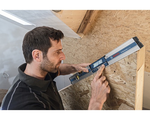 Muž používá digitální vodováhu Bosch k měření dřeva