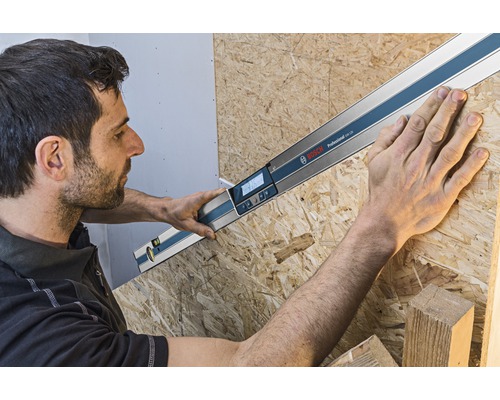 Řemeslník měří úhel s digitálním úhloměrem Bosch na dřevěné desce