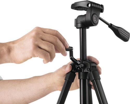Obsluha černého kamerového stativu s hlavou stativu rukama