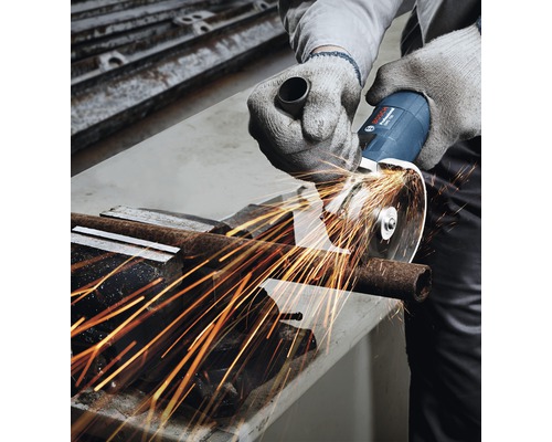 Osoba řeže kovovou trubku úhlovou bruskou, z níž odlétávají jiskry.