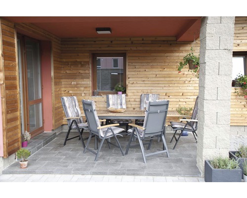 Venkovní posezení se stolem a židlemi na terase před dřevěným domem