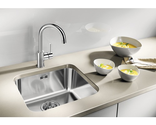 Nerezový dřez s baterií a třemi miskami polévky na pracovní desce