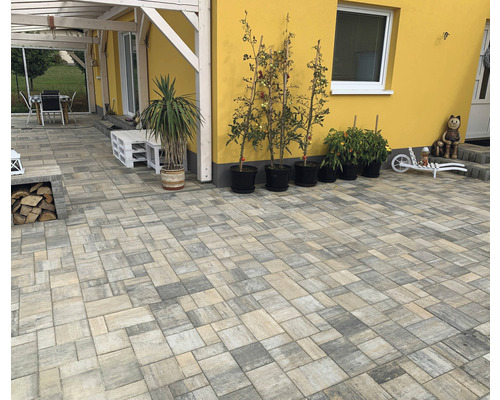 Dlážděná terasa s dlažebními kostkami, zahradním nábytkem a květináči