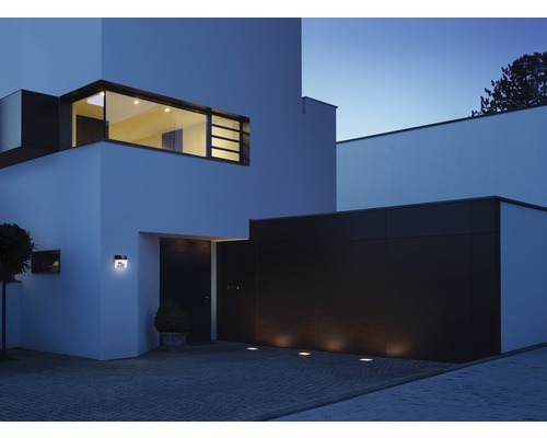 Moderní dům s venkovním osvětlením na fasádě a příjezdové cestě