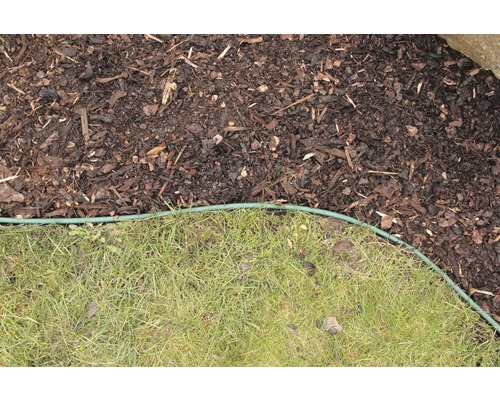 Zahrada s mulčovací kůrou a trávníkem, oddělené zeleným obrubníkem