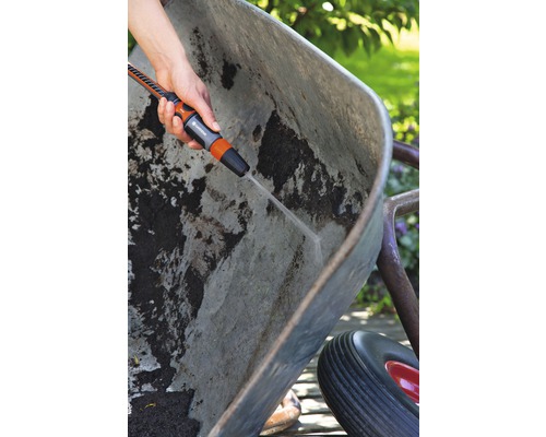 Osoba čistí špinavé kolečko zahradním postřikovačem.