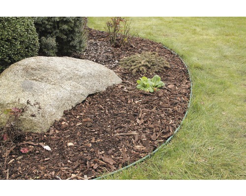 Zahradní scéna s mulčovací kůrou, kamenem a okrajem trávníku
