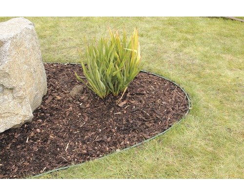 Ohraničení záhonu v zahradě s mulčovací kůrou, rostlinou a kamenem