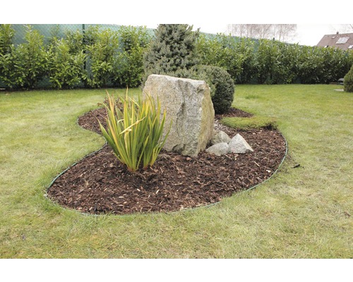 Zahradní scéna s trávníkem, kůrou stromů a velkým kamenem