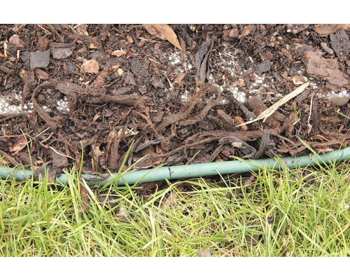 Detailní záběr mulčovací kůry, zahradní hadice a trávy