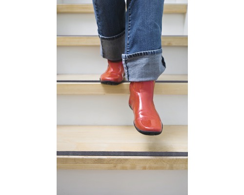 Osoba v botách schází po schodech s protiskluzovými páskami