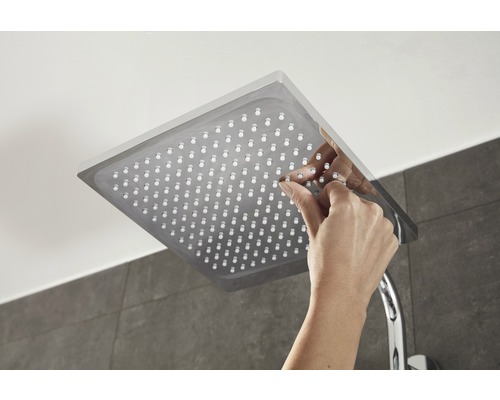 Čtvercová sprchová hlavice s rukou, která čistí trysky