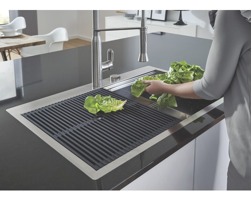 Nerezový dřez s odkapávací mřížkou a salátem v kuchyni