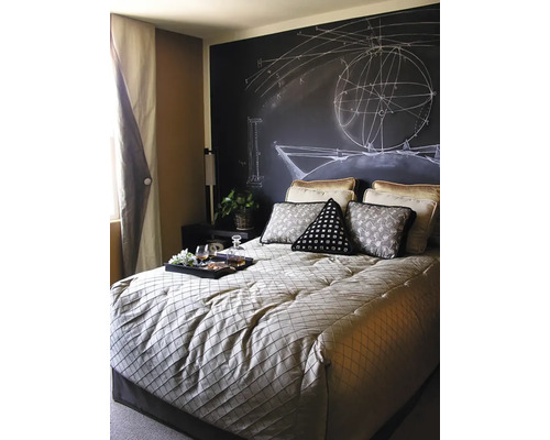 Ložnice s tabulovou stěnou a matematickými nákresy, postel s polštáři a podnos s nápoji.