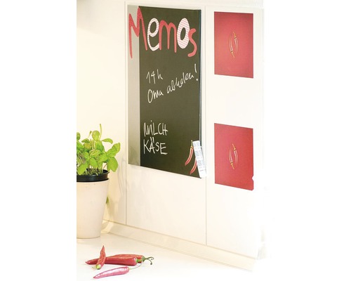 Nástěnka na poznámky vedle magnetů na lednici na kuchyňské stěně