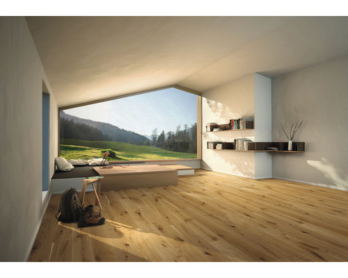 Světlá místnost s dřevěnou podlahou, velké okno s výhledem na zelenou krajinu, police a minimalistický nábytek
