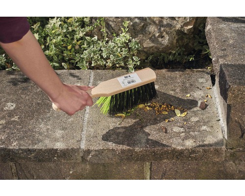 Ruka zametá kamenné schody koštětem