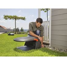 Muž instaluje robotickou sekačku na trávu na zahradě