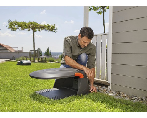 Muž instaluje robotickou sekačku na trávu na zahradě