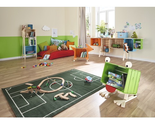 Dětský pokoj s postelí, regály z dřevěných beden a zeleným kobercem se vzorem fotbalového hřiště.