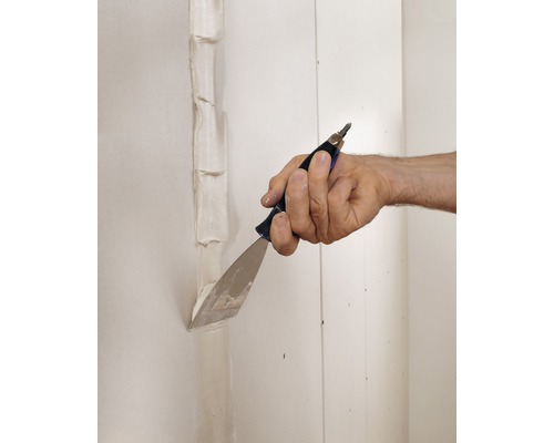 Osoba používá špachtli k nanášení tmelu na stěny.