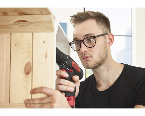 Muž pracuje s akumulátorovým šroubovákem na dřevěné polici