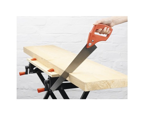 Ruční pila při řezání kusu dřeva na pracovním stole