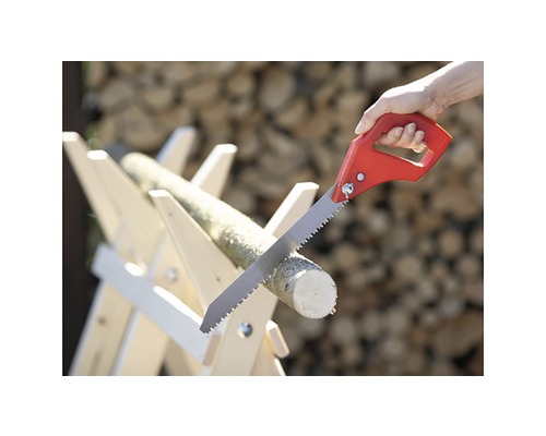 Ruční pila řeže kus dřeva na dřevěné koze