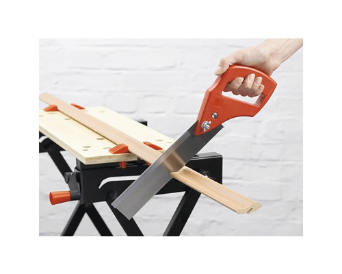 Ruční pila řeže dřevěnou lištu na pracovním stole