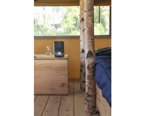 Interiér stanu s dřevěnou podlahou, nočním stolkem, topením a postelí