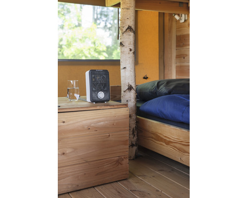 Interiér s postelí, dřevěnou podlahou, nočním stolkem, sklenicí vody a topením